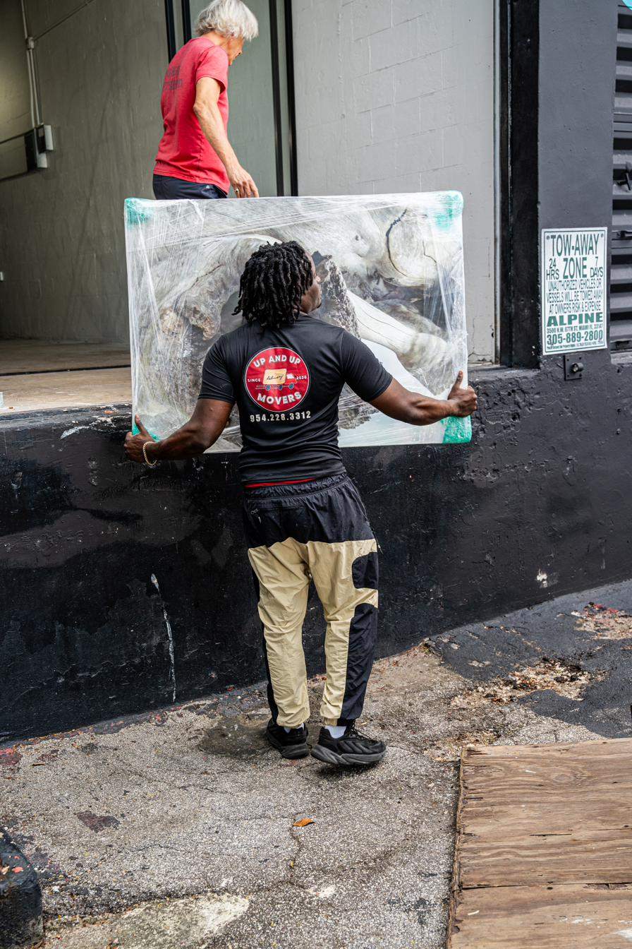 Up and Up mover hand-carrying wrapped artwork during a Broward County move